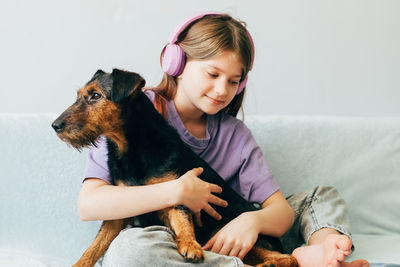 Young woman with dog sitting on sofa at home