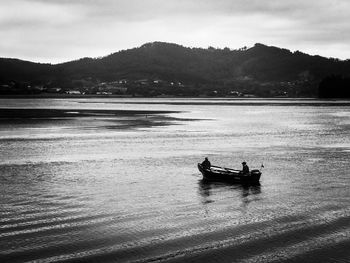 People in boat on sea against mountain