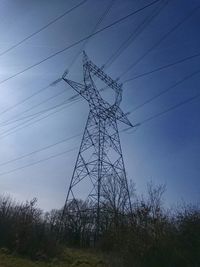 Low angle view of electricity pylon on field