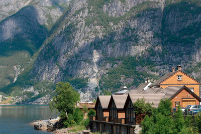 Houses and trees by lake against mountain