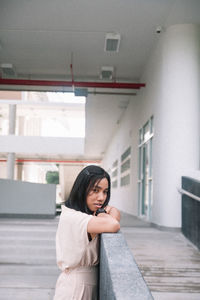 Portrait of young woman standing against wall