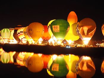 Reflection of illuminated lights on river against sky at night