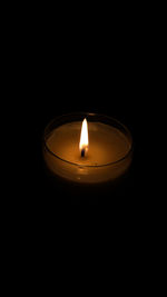 Close-up of lit candle against black background