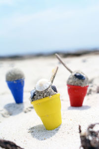 Ice cream made of toys and sand at beach against sky during sunny day