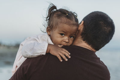 Dad and daughter hugging in the ocean at dusk