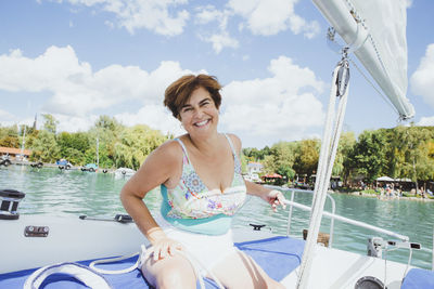 Happy woman enjoying vacation sitting on sailboat