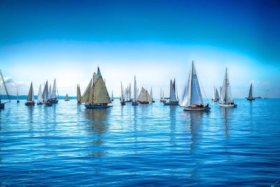 Sailboats sailing in sea against sky