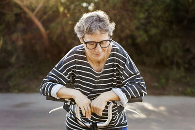 Woman wearing eyeglasses standing with bicycle on road