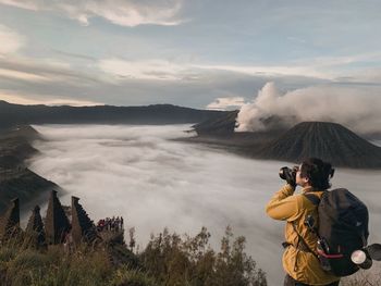 Rear view of man photographing against sky