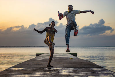 Full length of man jumping on beach against sky during sunset