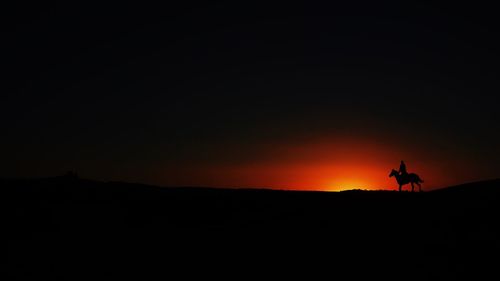 Silhouette man walking on landscape at sunset