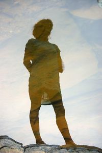 Mid adult woman standing against sky reflecting on calm lake