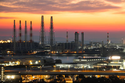 Illuminated factory against sky at sunset