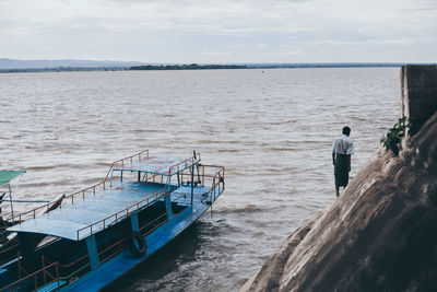 Rear view of man standing in sea against sky