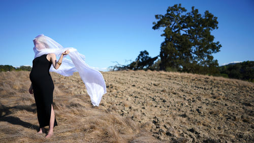 Rear view of woman on field against clear sky