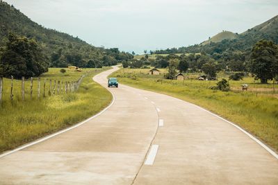 Road amidst green landscape against sky