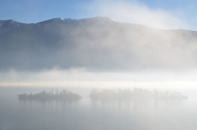 Scenic view of lake against sky during foggy weather