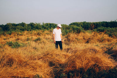 Rear view of man standing on field against clear sky