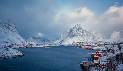 Scenic view of sea by snowcapped mountains against sky