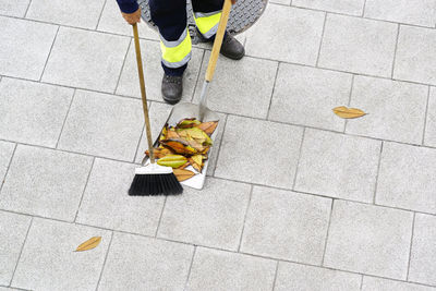 Low section of person cleaning footpath with broom and shovel 