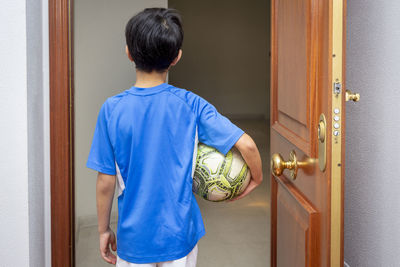 Rear view of man standing against door