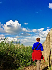 Woman walking by plants against sky