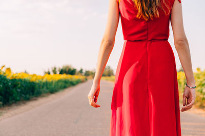 Midsection of woman standing by road against sky