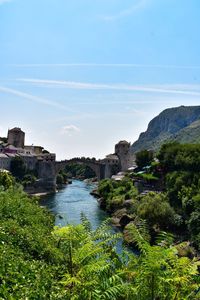 Scenic view of river by buildings against sky