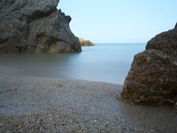 Rocks on beach against clear sky