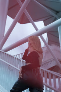 Low angle view of woman standing on railing