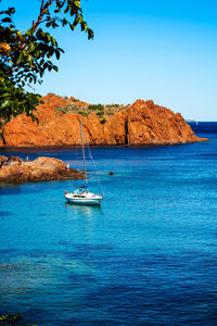 Sailboat sailing on sea against clear blue sky