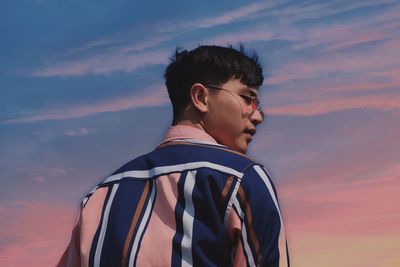 Portrait of young man looking away against sky during sunset