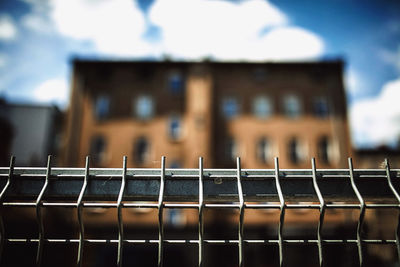 Close-up of metallic fence against buildings