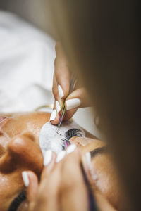 Close-up of human hand holding ring on bed