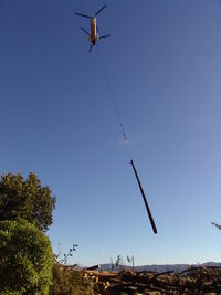 Low angle view of helicopter against clear sky