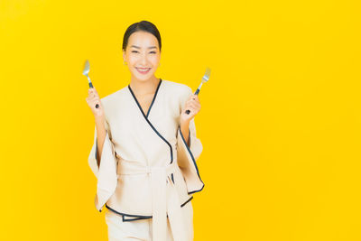 Portrait of a smiling young woman against yellow background