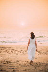 Rear view of woman standing at beach