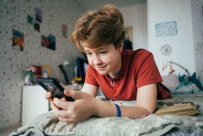 Teenage girl lying on the bed writes messages on the phone.