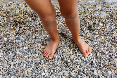 Barefeet child legs standing in the water in pebbles beach