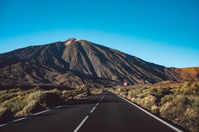 Road by mountain against blue sky