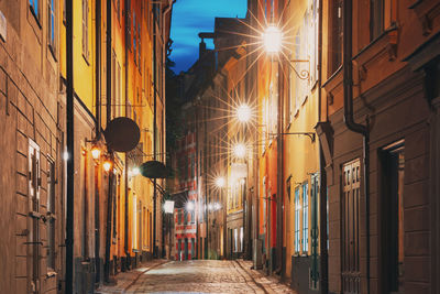 Illuminated street amidst buildings in city at night