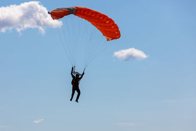 Low angle view of person paragliding against sky