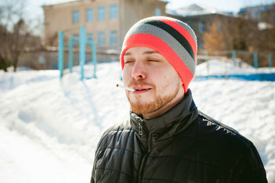 Close-up of man in warm clothing smoking cigarette