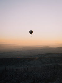 Hot air balloon flying over landscape against sky during sunset