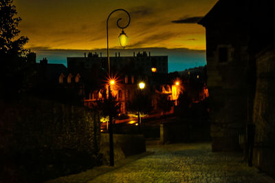 Illuminated street light against sky at night