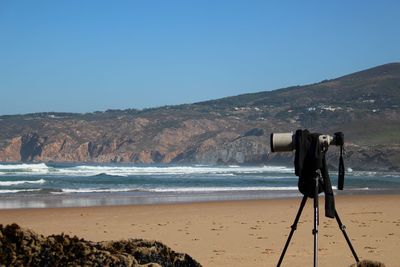 Rear view of person photographing sea against clear sky