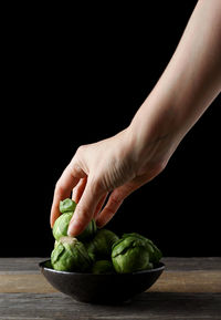 Close-up of hand holding food against black background