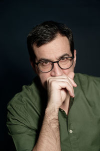 Portrait of man wearing eyeglasses against black background