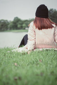 Rear view of woman sitting on field