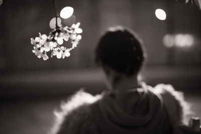 Rear view of woman standing on illuminated flowering plant
